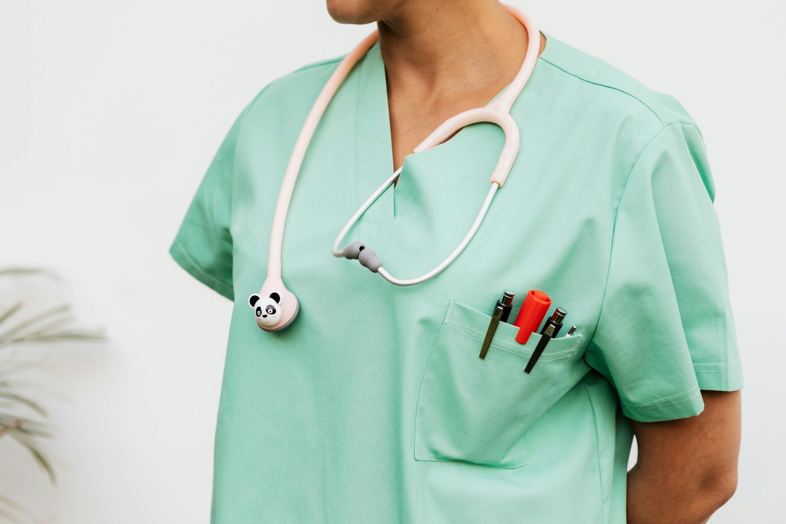 Close-up of a doctor in scrubs with a panda themed stethoscope and pocket pens.